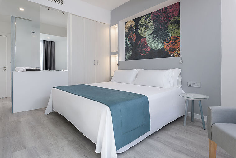 Blick in ein helles Zimmer mit Doppelbett