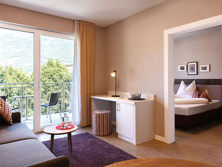 Blick in einen Wohnbereich mit Sofa und Blick in ein Schlafzimmer