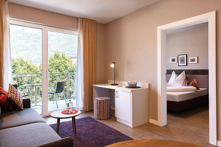 Blick in einen Wohnbereich mit Sofa und Blick in ein Schlafzimmer