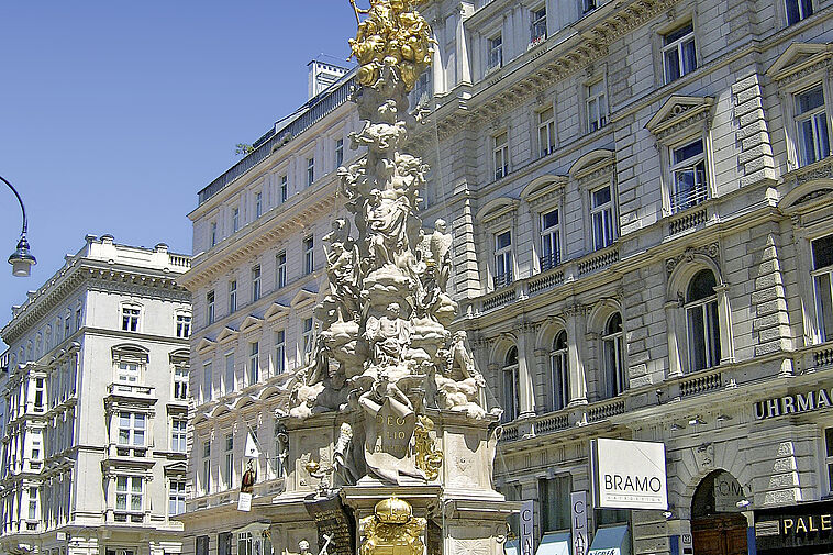 Blick auf einen Platz mit Brunnen und Fassaden im Hintergrund