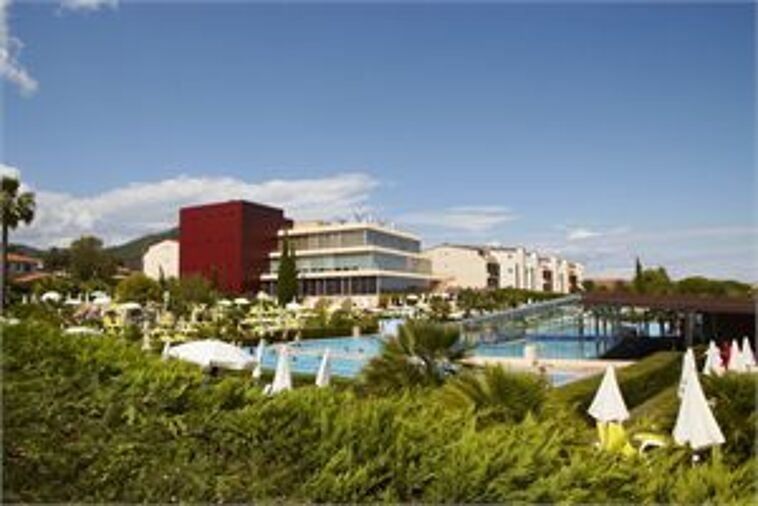 Blick über einen Garten und Pool auf ein Hotel