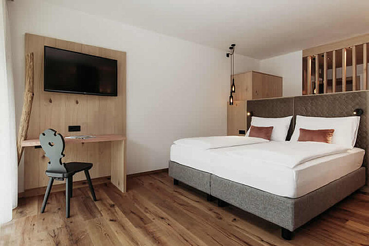 Blick in ein Doppelzimmer mit Holzfußboden und Bett