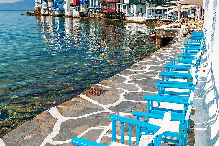 Blaue Stühle am Meer auf Mykonos